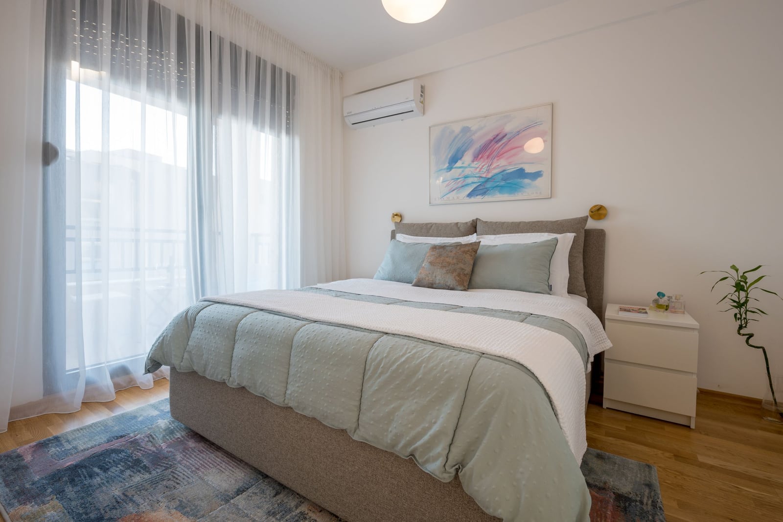 Cozy bedroom with a double bed in a Tivat apartment, Montenegro: bright interior, air conditioning, and balcony access.