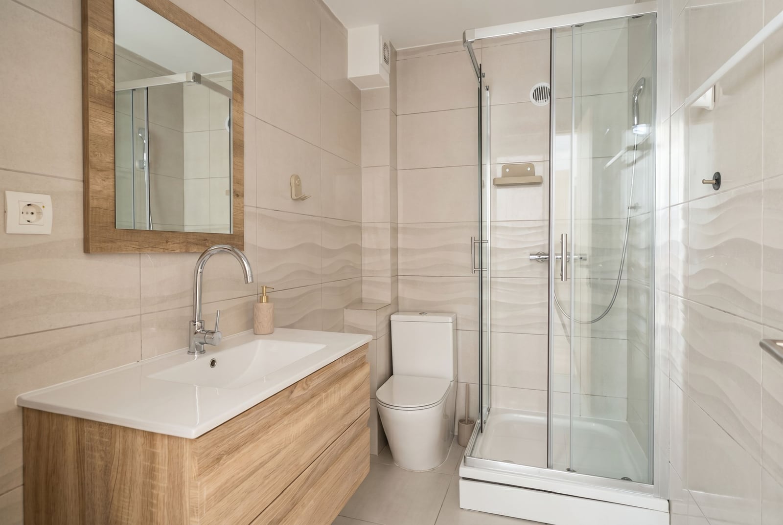 Modern bathroom in an apartment in Budva, Montenegro: shower cabin, vanity unit, and light-colored tiles.