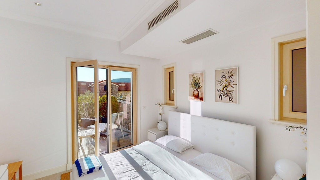 Bright bedroom in an apartment in Luštica, Montenegro: double bed, terrace access, and modern finishes.