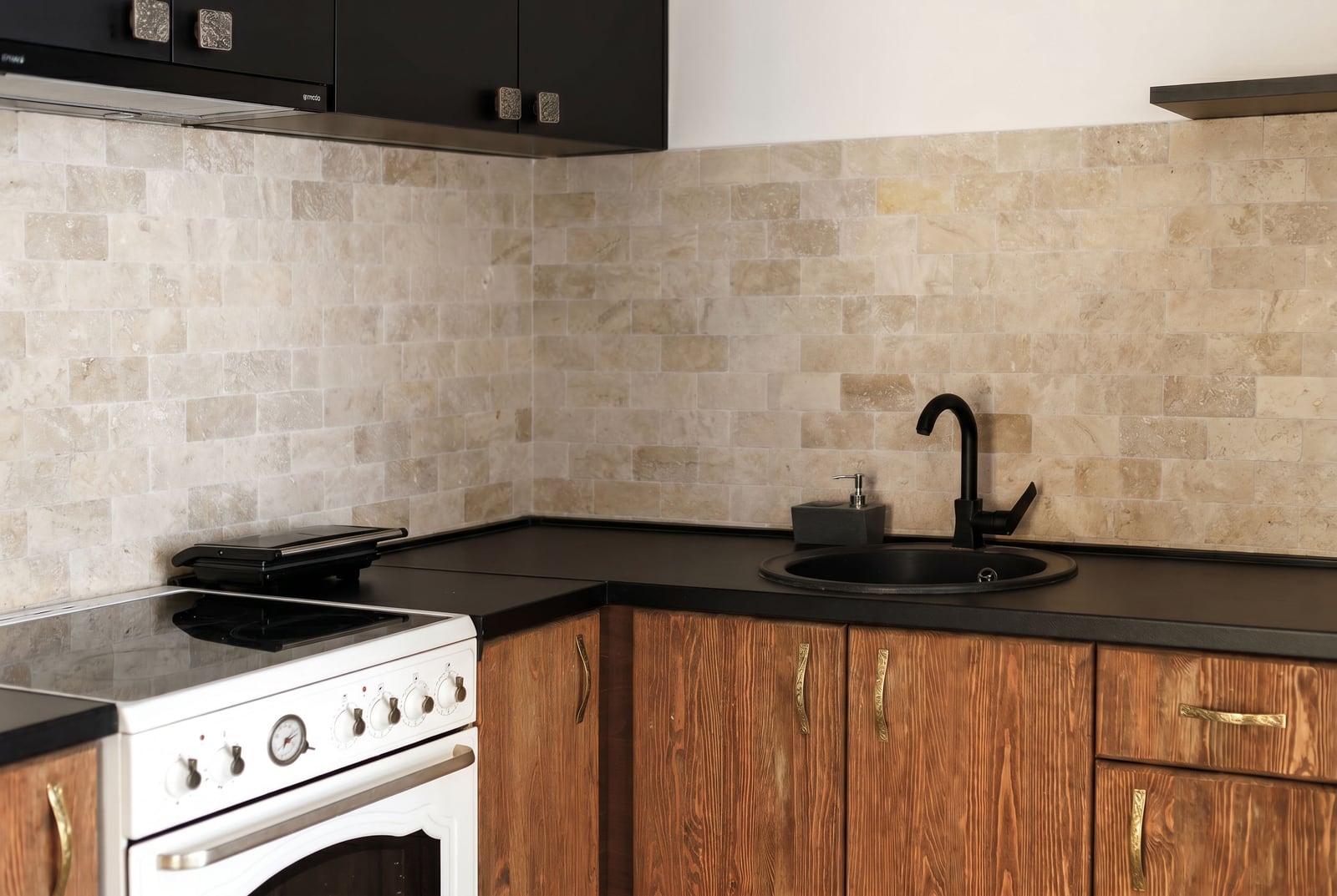 Modern kitchen in an apartment in Risan, Montenegro: wooden facades, black countertop, and stone backsplash.
