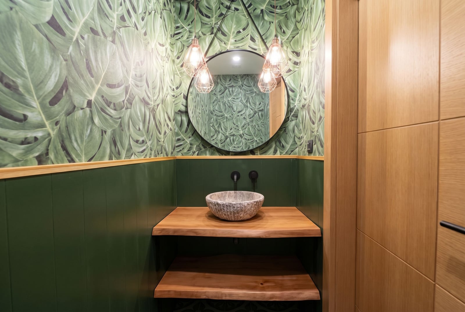 Designer bathroom in a villa in Kavac, Montenegro: stone sink, wooden countertop, and tropical wallpaper.