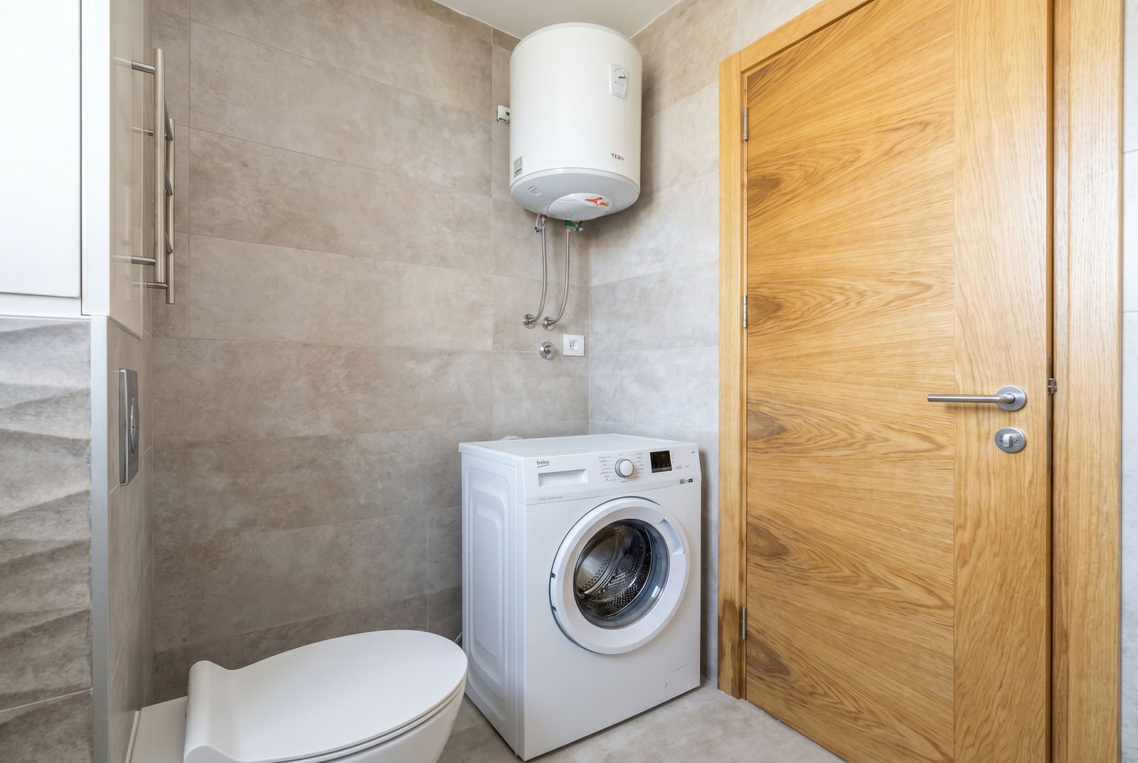 Bathroom in an apartment in Becici, Montenegro: washing machine, water heater, modern tile finish, and door.