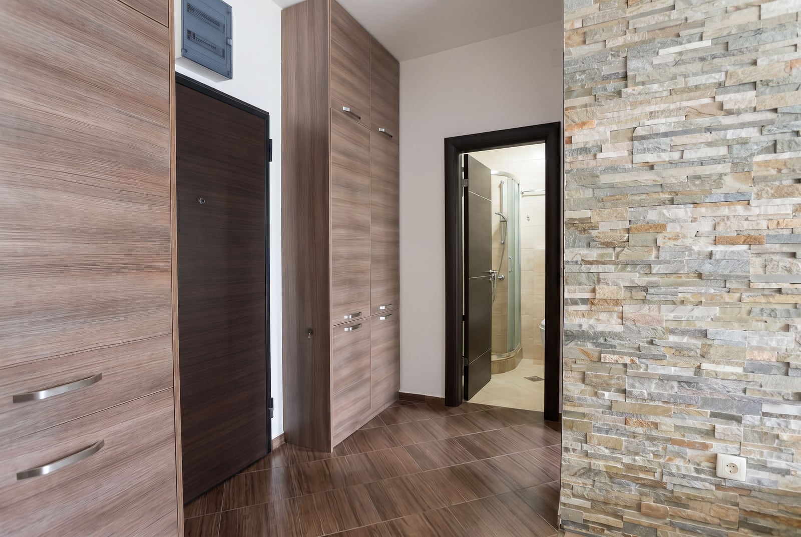 Modern hallway with built-in wooden wardrobes and stone finishing in an apartment in Budva, Montenegro.