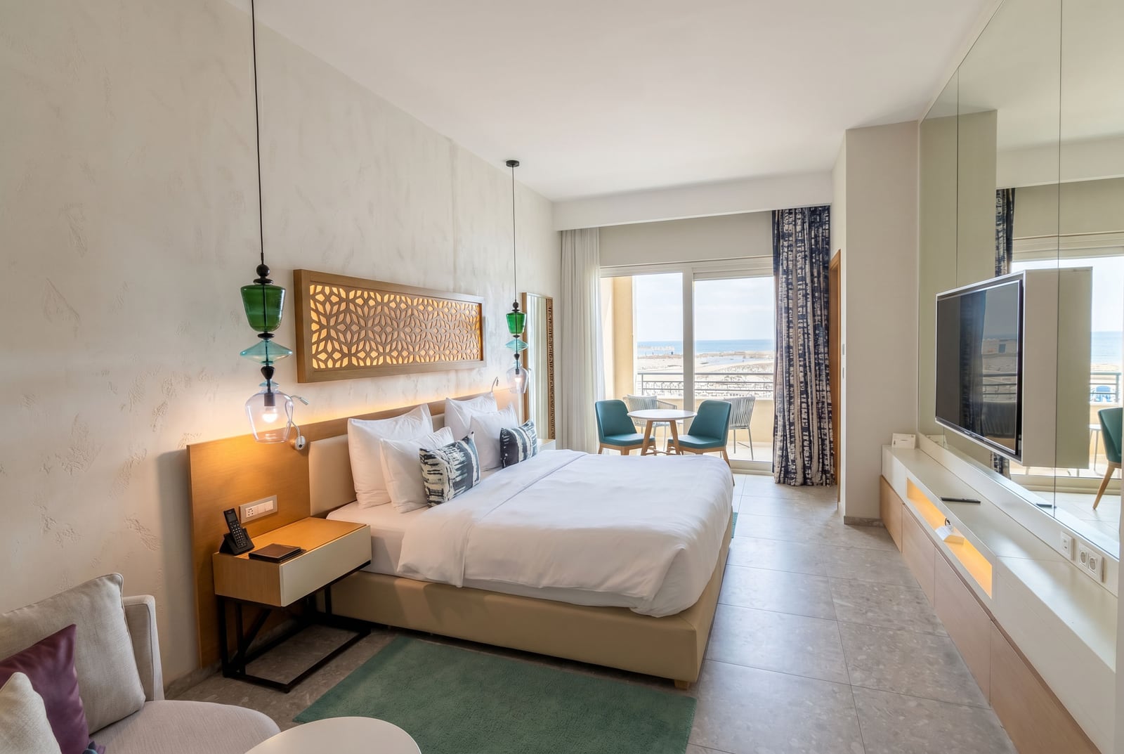 Modern bedroom at Luštica Bay hotel, Montenegro: double bed, sea view from the balcony, and stylish interior.