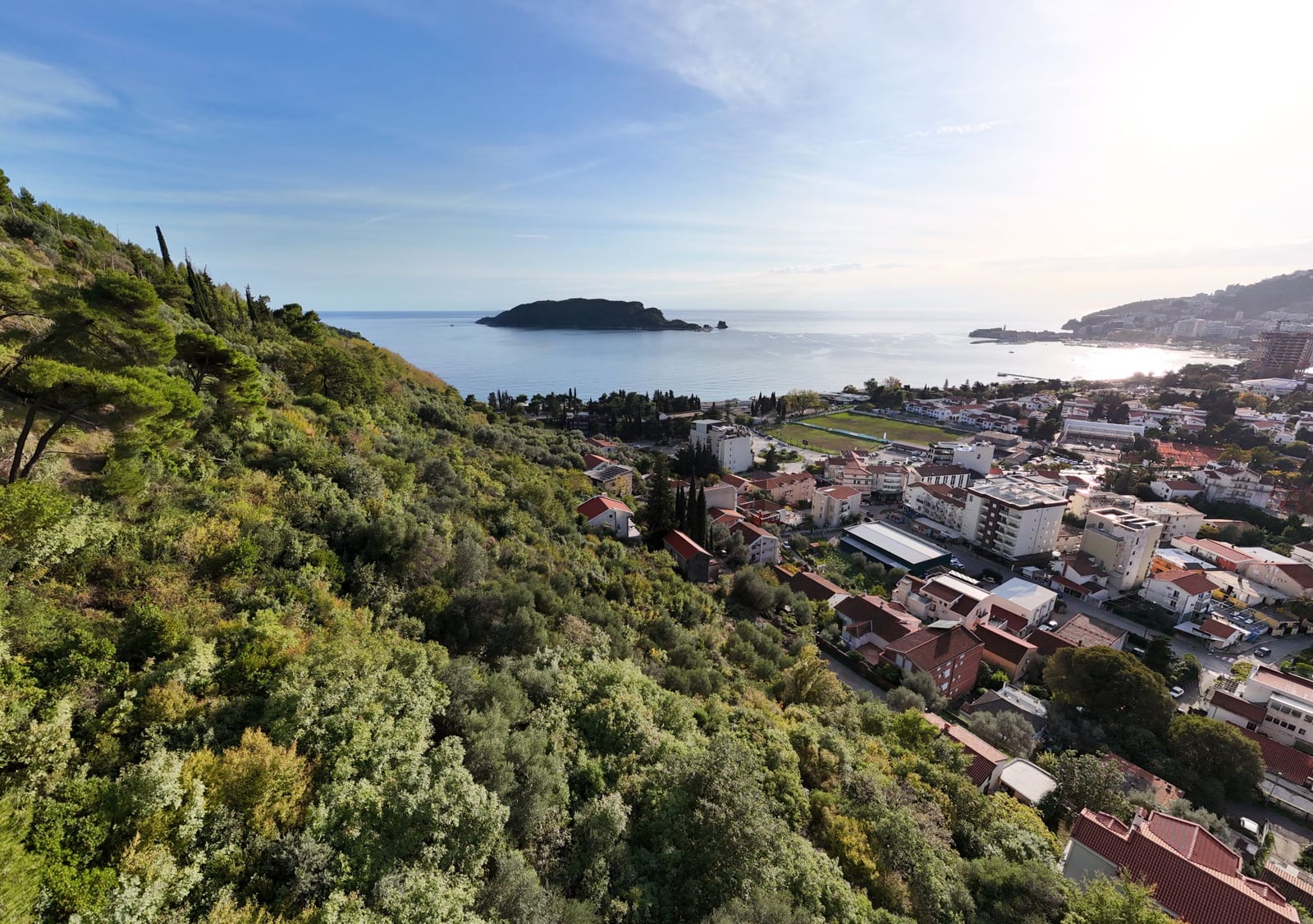 Panoramic view of Budva city and the island of Sveti Nikola, Montenegro, from a hillside plot of land.
