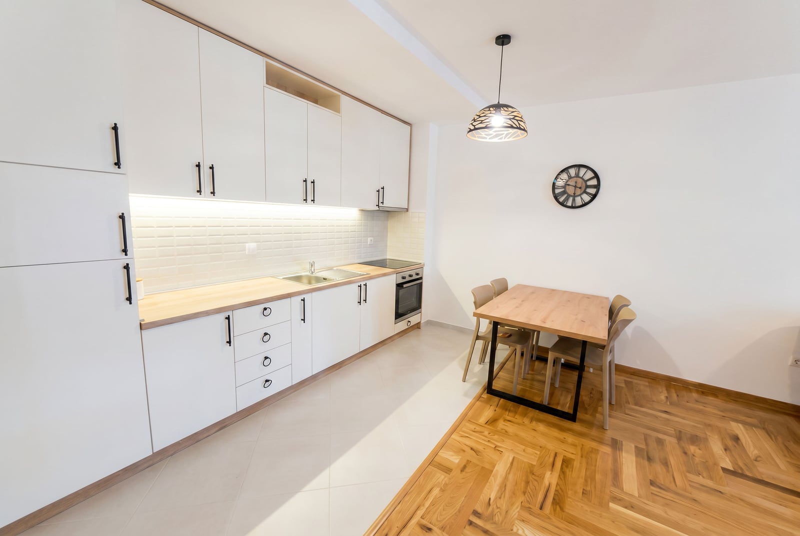 Modern kitchen with white cabinetry and dining area in an apartment, Rafailovici, Montenegro.