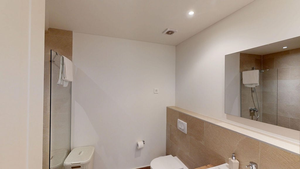 Modern bathroom with a shower cabin in an apartment, Luštica, Montenegro: light finishes and a large mirror.