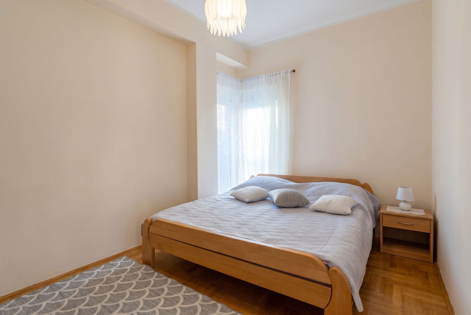 Cozy bedroom with a double bed and parquet flooring in an apartment for sale in Budva, Montenegro.