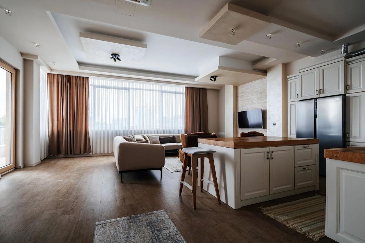 Modern living room with kitchen and island in an apartment, Budva, Montenegro: bright interior, panoramic windows, and decor.