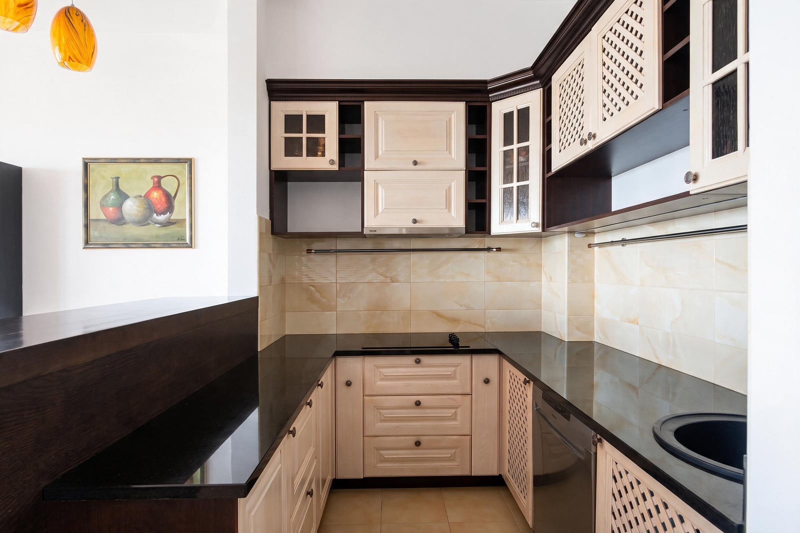 Kitchen with beige-brown classic cabinets and a black countertop in an apartment in Bečići, Montenegro.