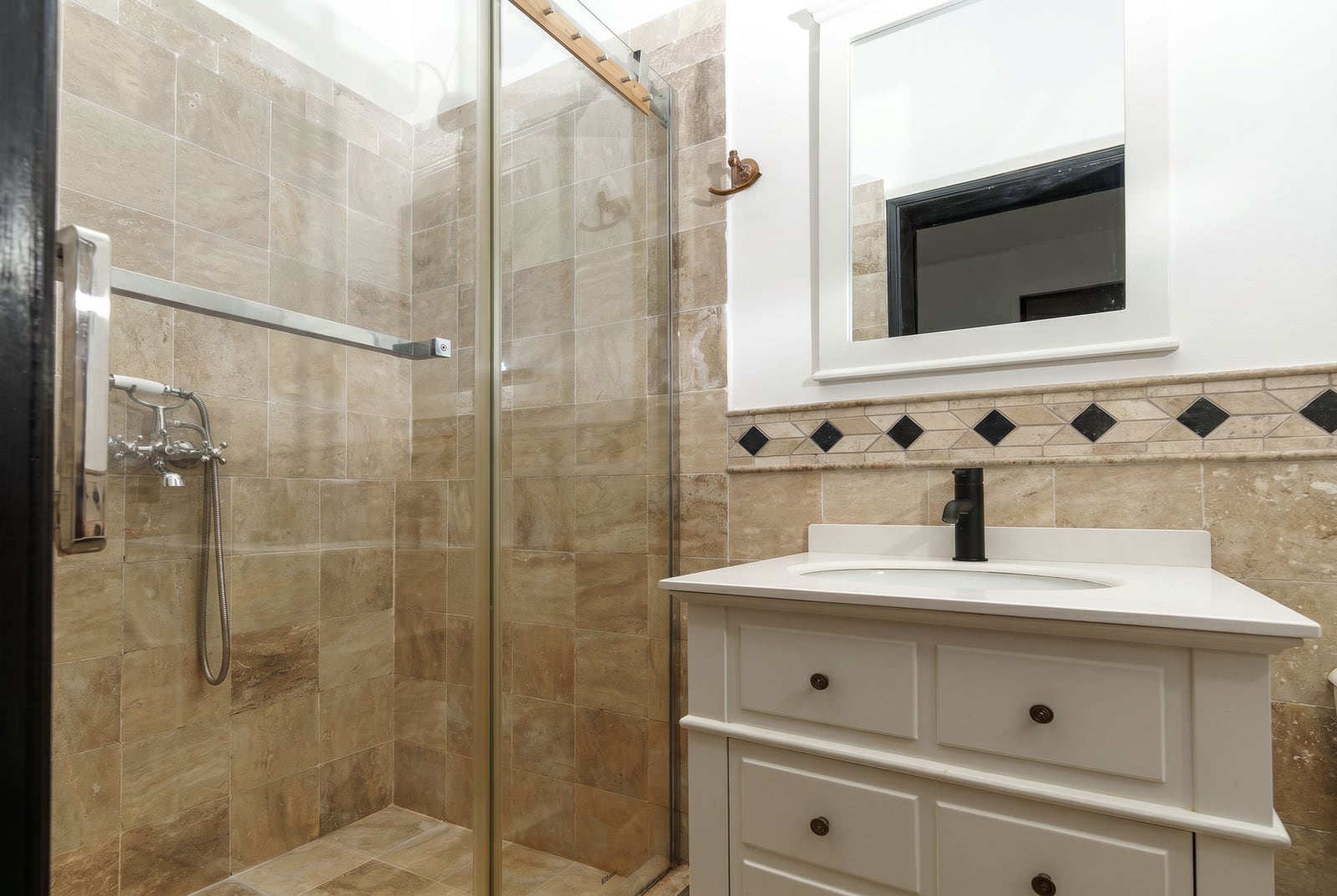 Bathroom in an apartment in Risan, Montenegro: shower cabin, white vanity unit with sink, and beige tile finish.