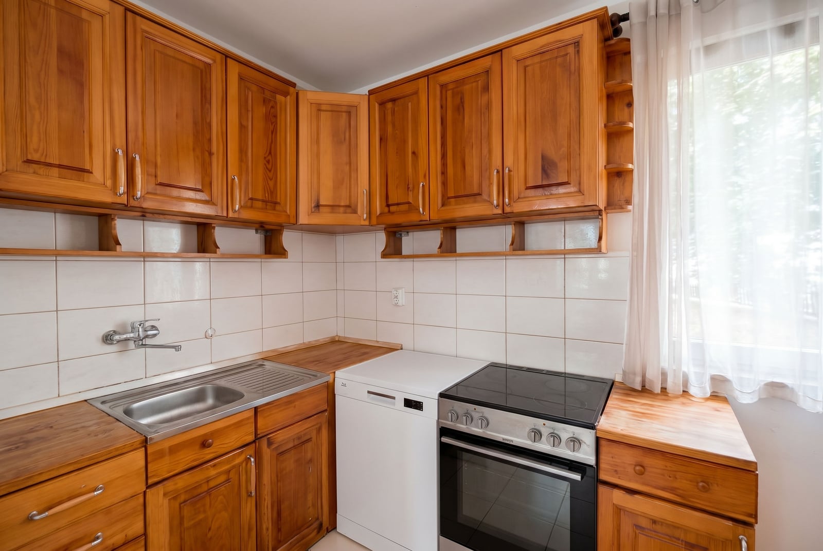 Cozy kitchen with wooden cabinetry and appliances in an apartment for sale, Budva, Montenegro.