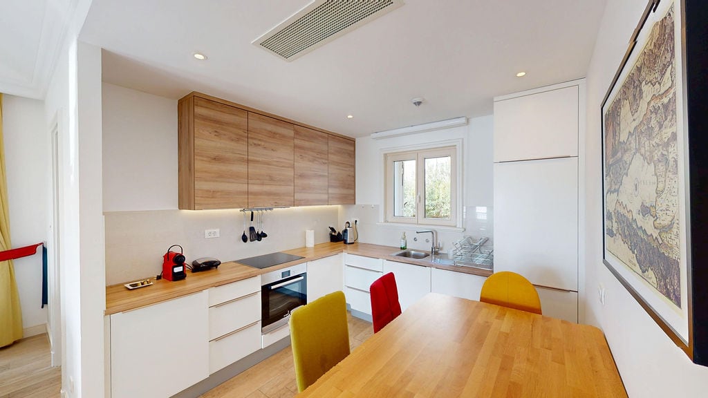 Modern kitchen in an apartment in Luštica, Montenegro: light-colored cabinets, wooden countertop, and dining area.