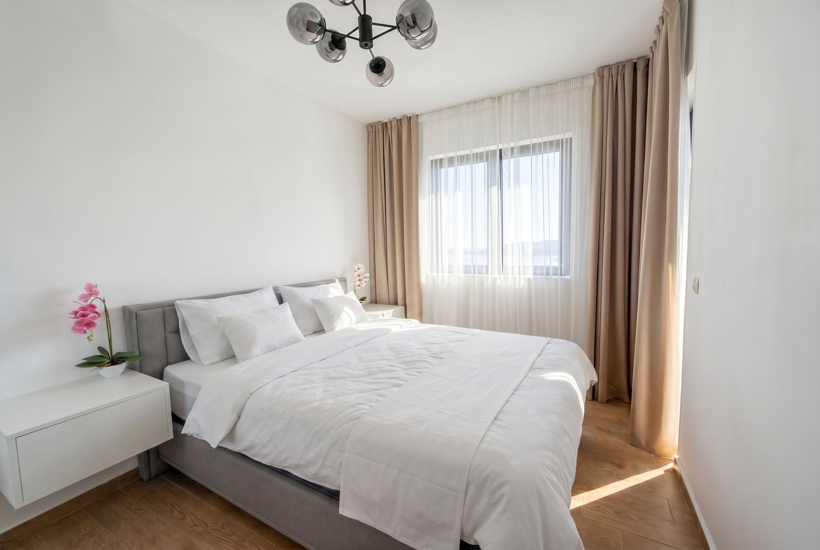 Bright bedroom in a Becici residential complex apartment, Montenegro: double bed, modern furniture, and panoramic curtains.