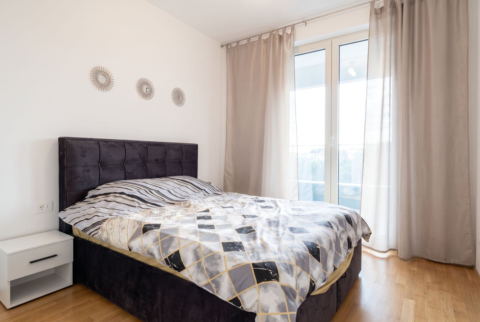 Cozy bedroom with a double bed and balcony access in an apartment in Bečići, Montenegro. Modern interior.