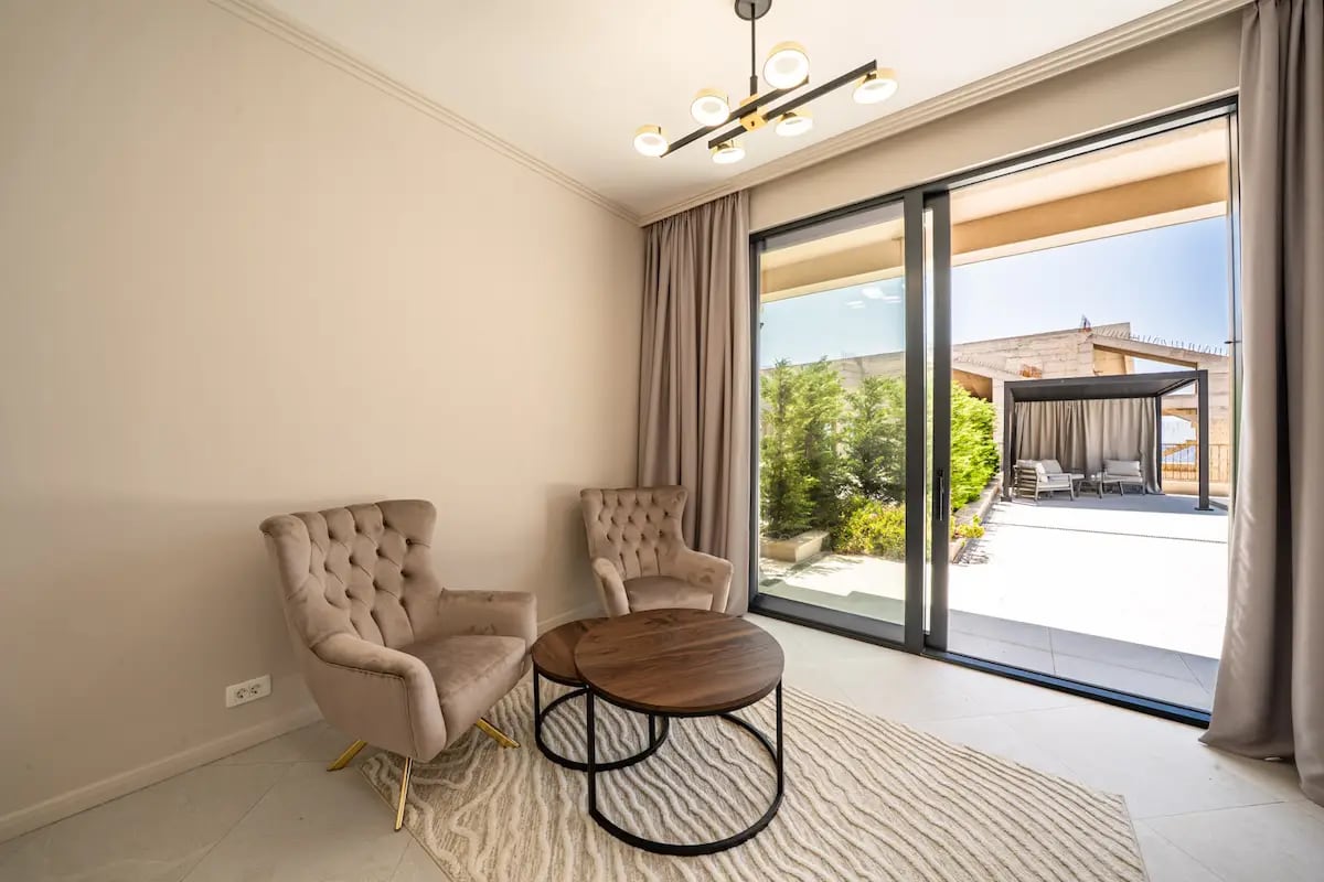 Living room with comfortable armchairs and a terrace in a villa in Reževići, Montenegro: modern interior with panoramic glazing.