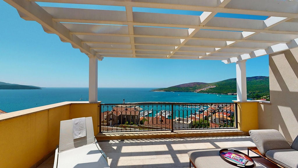 Terrace with a pergola and sea and marina views in the Luštica residential complex, Montenegro: sun loungers and relaxation furniture.