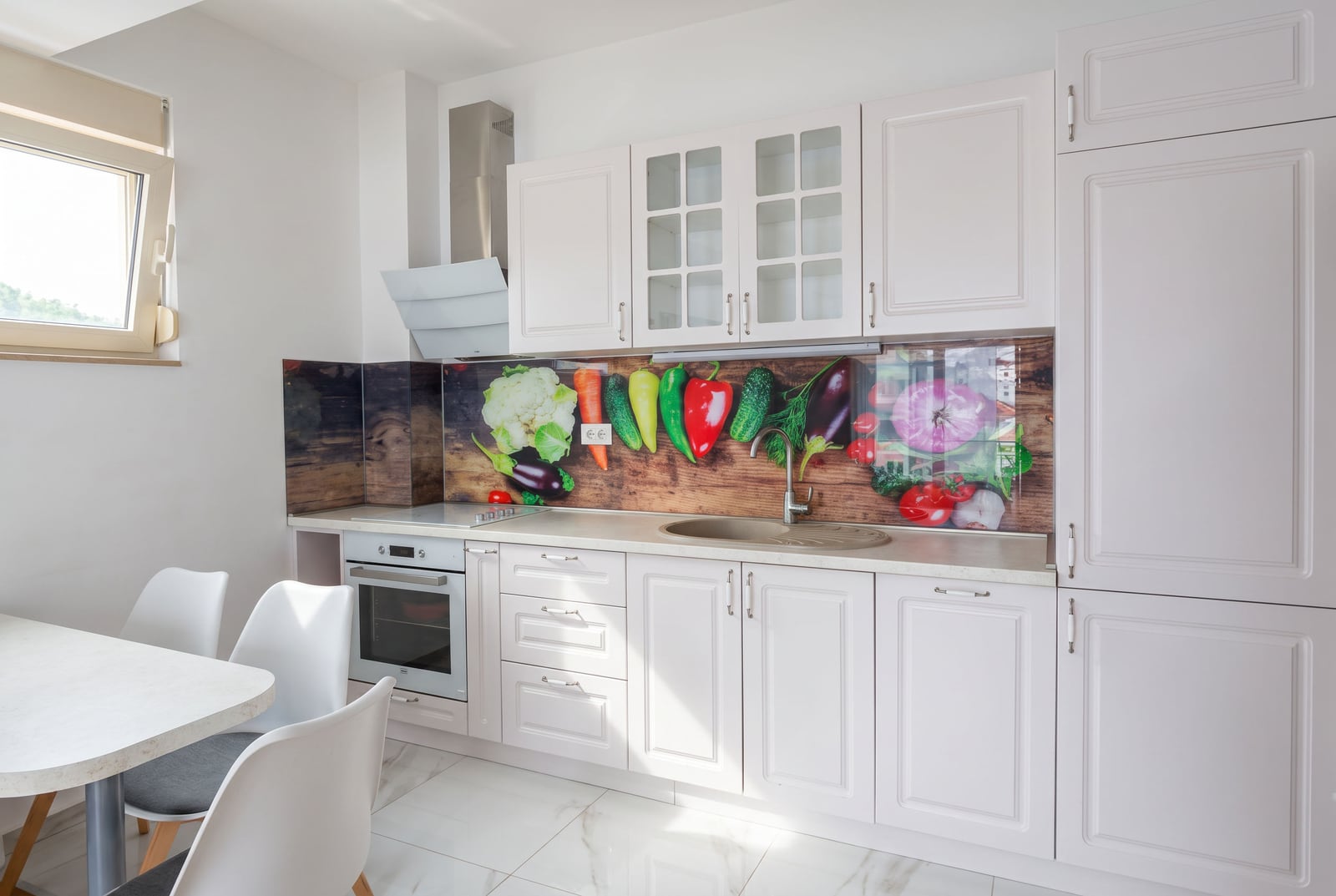 Kitchen with white cabinets, built-in oven, sink, and a backsplash featuring a vegetable mural.