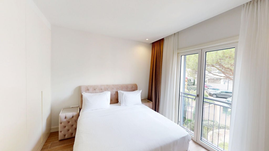 Bright bedroom with a double bed and balcony access in the Luštica Bay apartments, Montenegro.