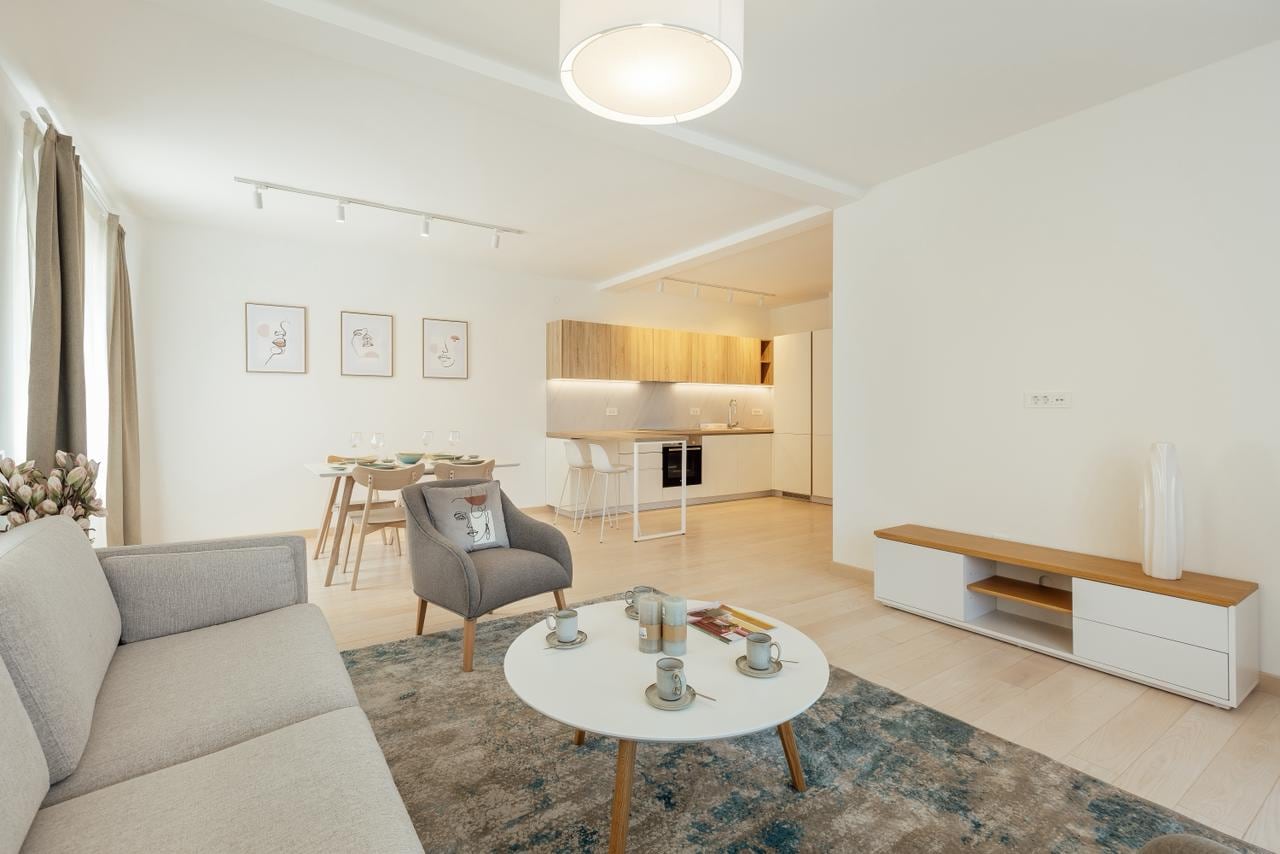 Modern living room with a kitchen in an apartment, Igalo, Montenegro: bright interior, upholstered furniture, and dining area.