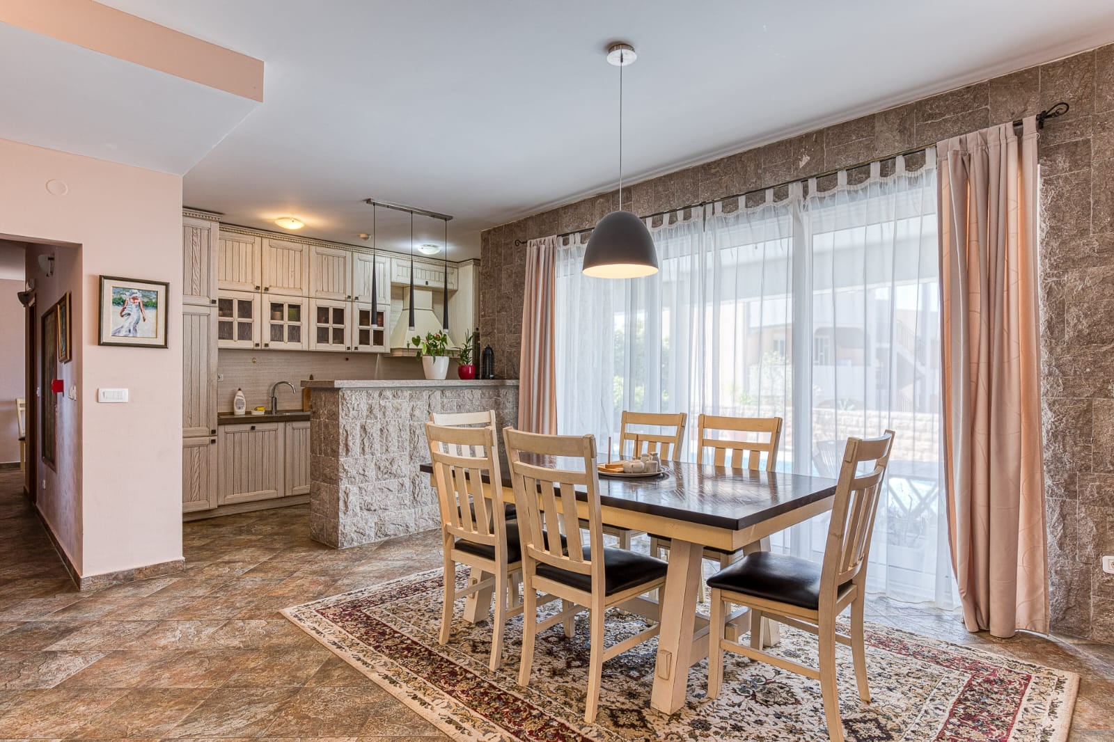 Kitchen-dining room with stone finishes and a dining area in a villa in Bečići, Montenegro. Modern interior with furniture.