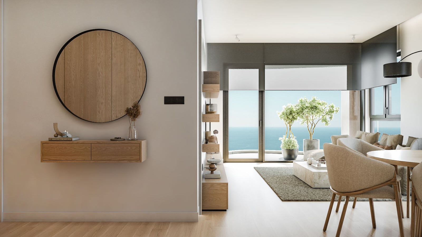 Modern living room with sofa, dining table, and round mirror overlooking the ocean through large windows.