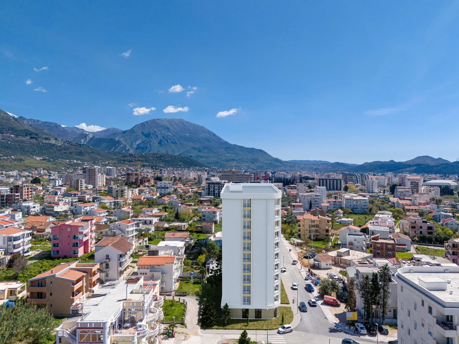 Aerial view of a modern residential complex in Bar, Montenegro, against a backdrop of scenic mountain landscapes.