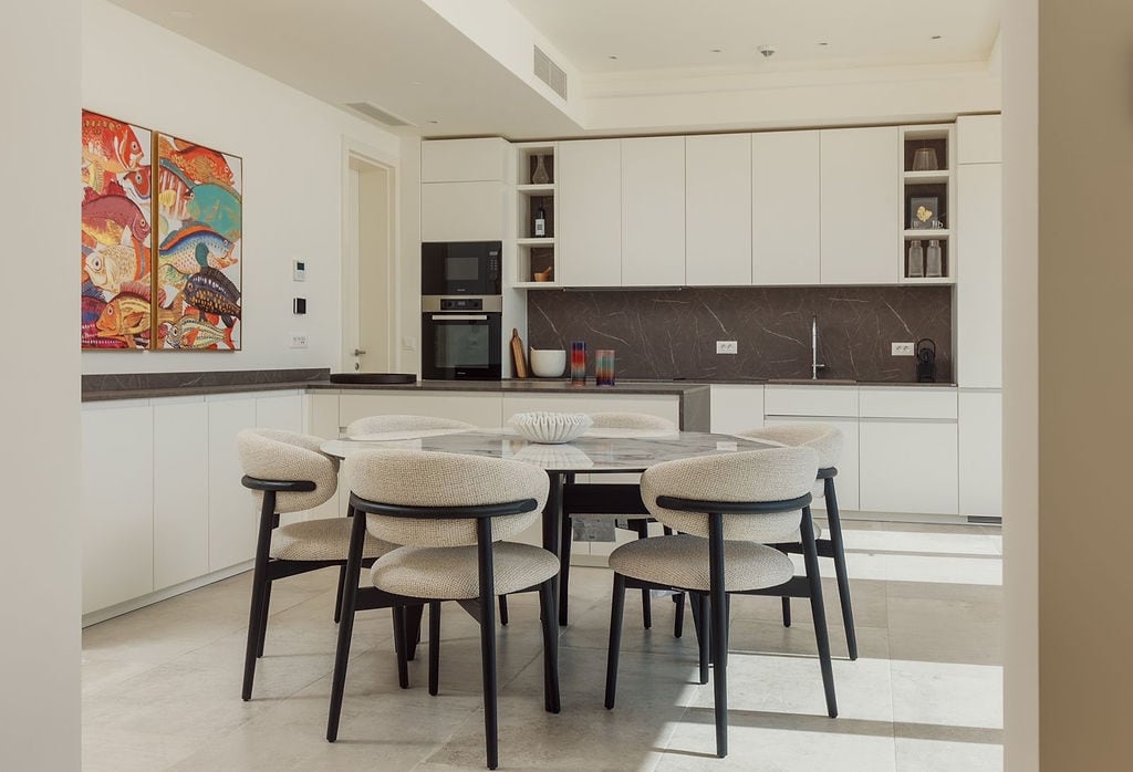 Modern kitchen-dining room with white cabinetry and a marble table at a villa in Luštica, Montenegro.