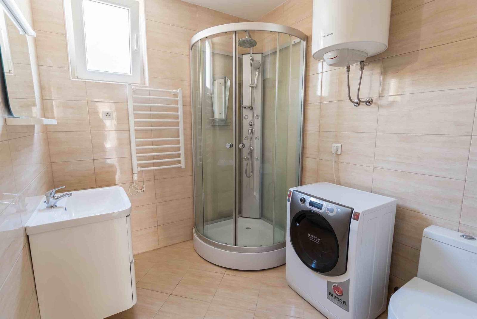 Modern bathroom in an apartment in Bečići, Montenegro: walk-in shower, washing machine, and Ariston water heater.