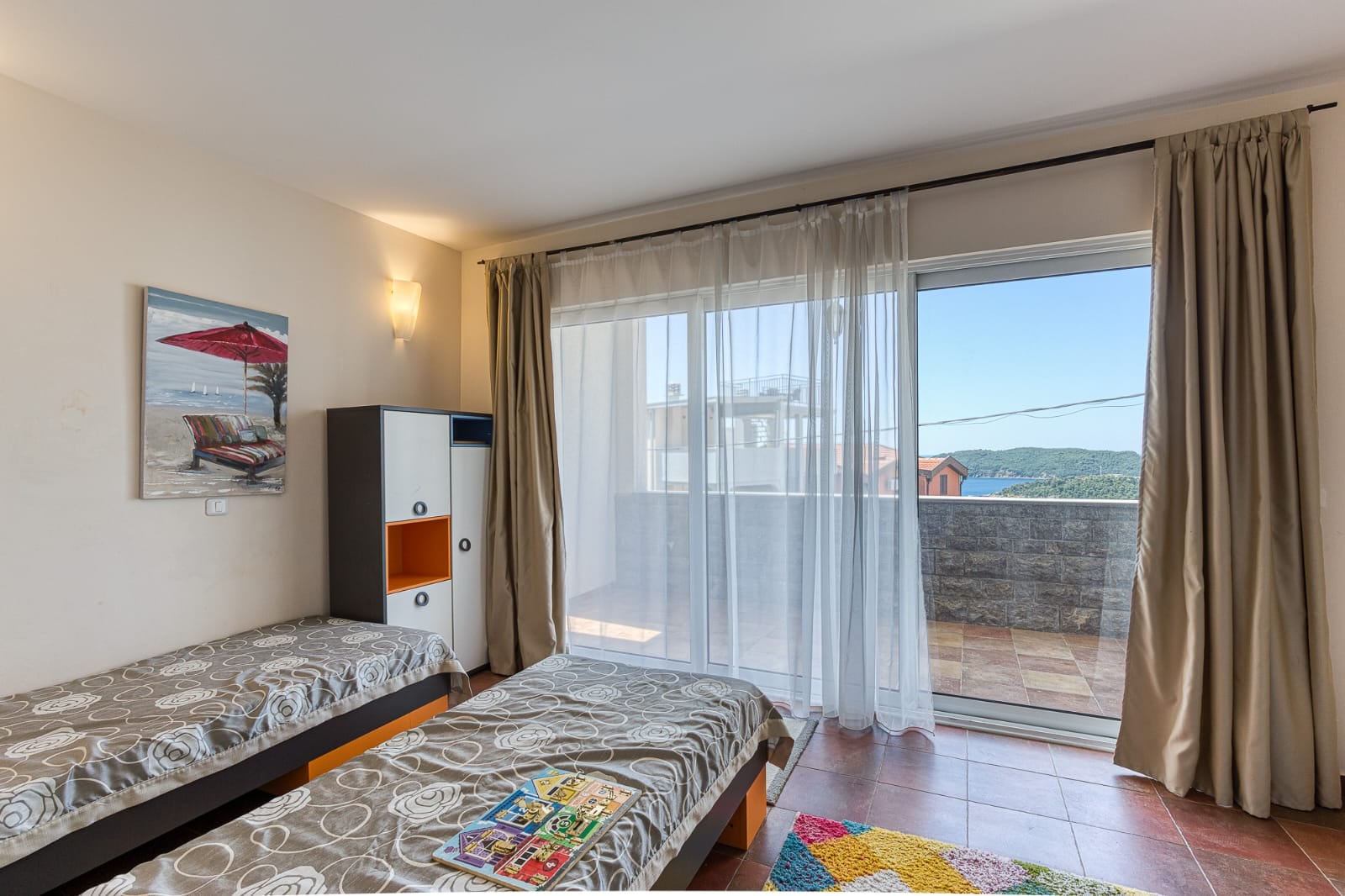 Bedroom with two beds and access to a terrace with a sea view in a villa in Becici, Montenegro.