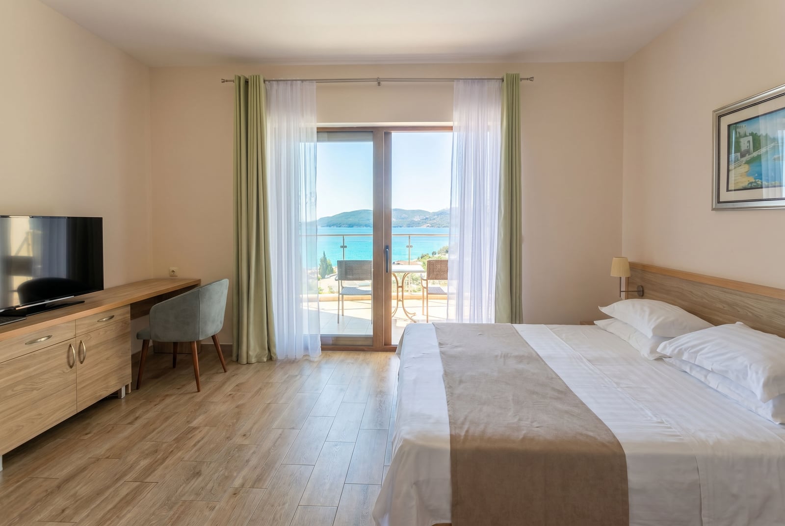 Bedroom in an apartment in Bečići, Montenegro: double bed, workspace, and a balcony with a panoramic sea view.