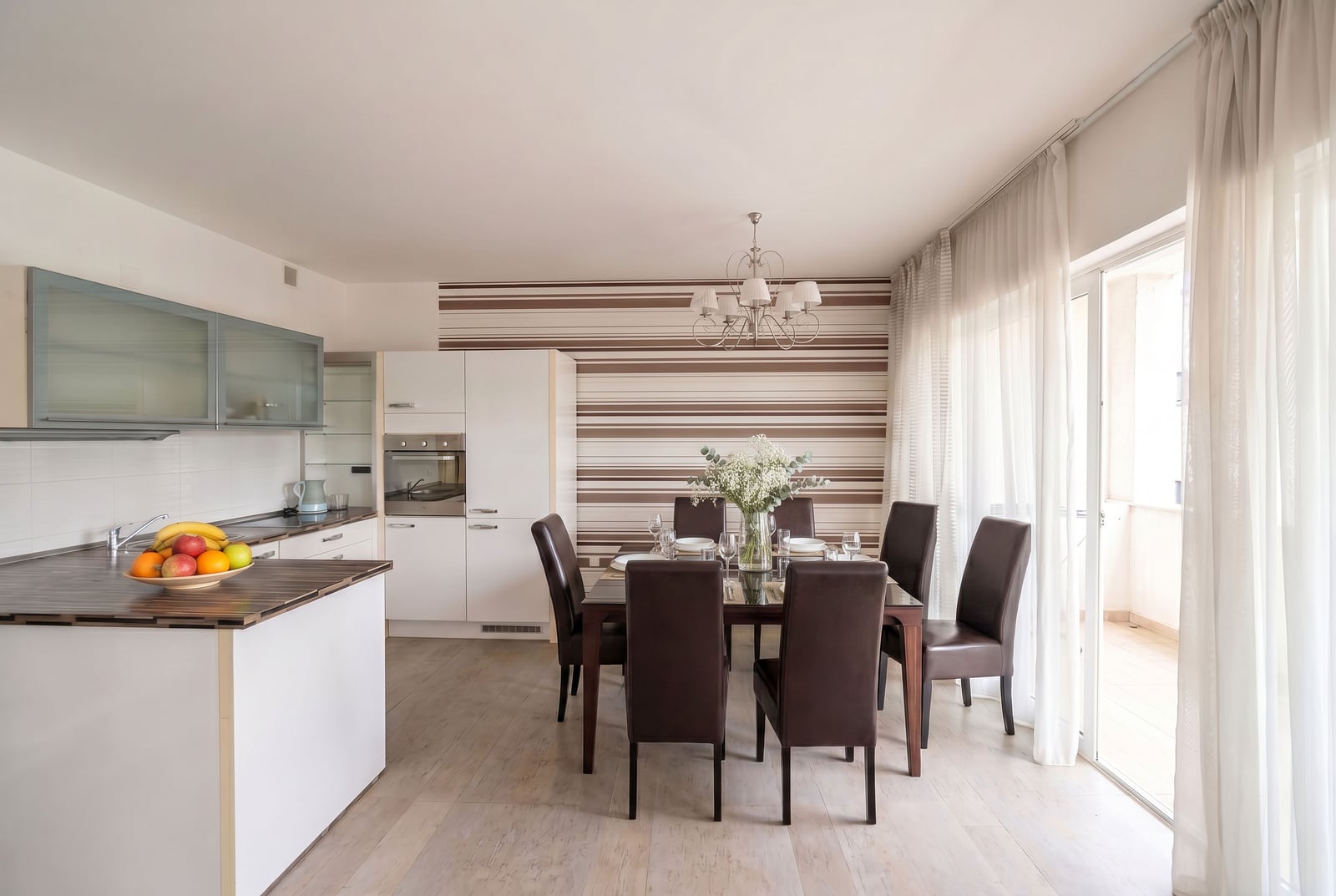 Modern kitchen-dining room with a dining area in a Kumbor apartment, Montenegro: bright interior and balcony access.