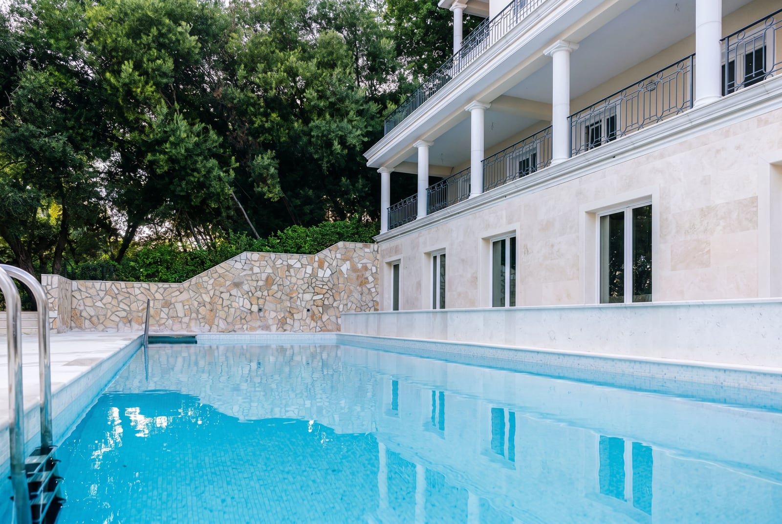 Luxury villa with a swimming pool and stone finishes in Kumbor, Montenegro: view of the facade with columns and a terrace.