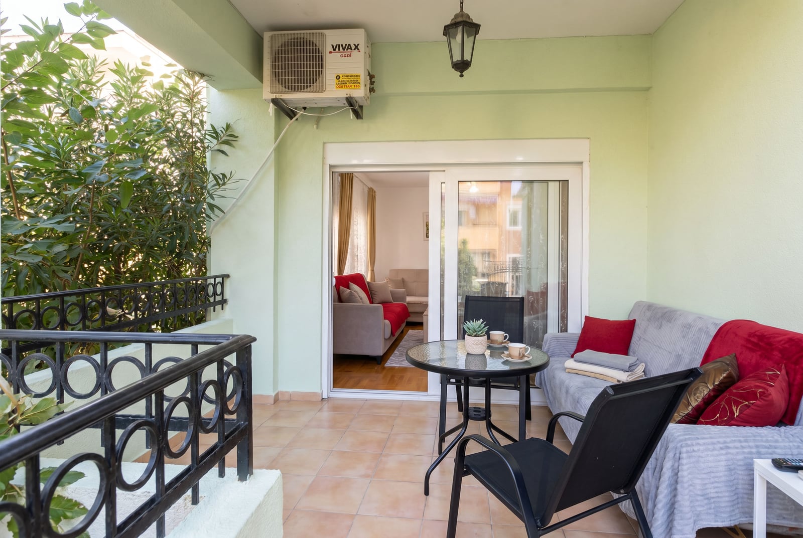 Cozy terrace with furniture and a view of the living room in an apartment, Budva, Montenegro. Tiled balcony with wrought iron railing.