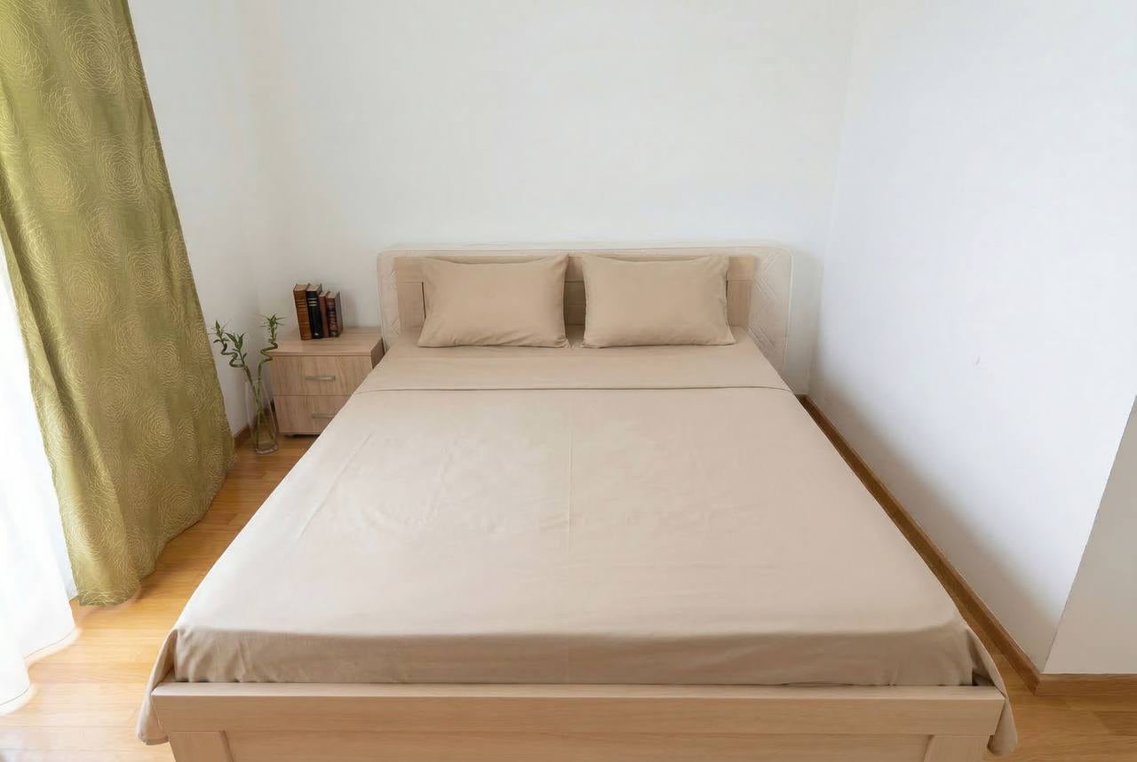 Cozy bedroom with a double bed in an apartment in Bečići, Montenegro: light-colored furniture, parquet flooring, and olive-colored curtains.