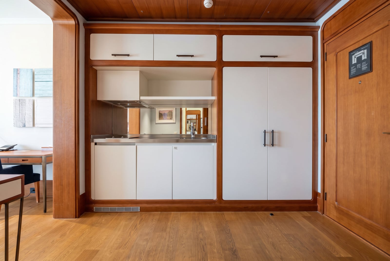 Built-in kitchen unit with white cabinets, stainless steel countertop, sink, and wooden frame.