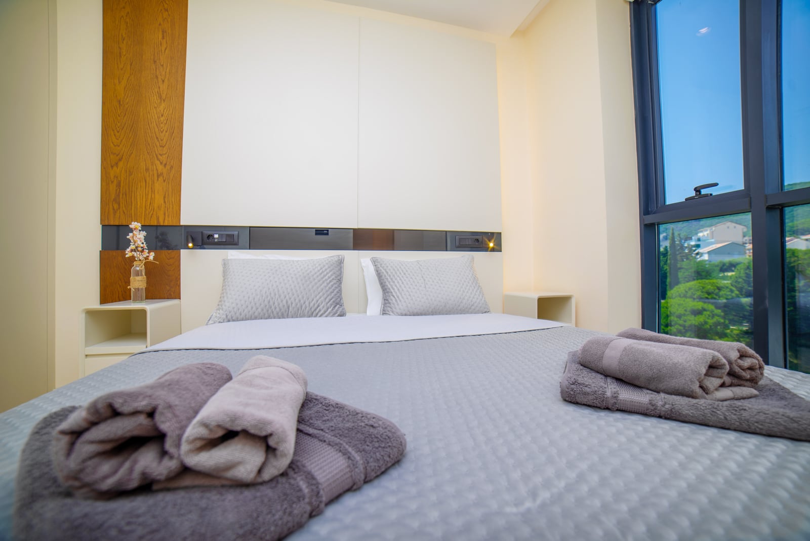 Modern bedroom in an apartment in Bečići, Montenegro: double bed, panoramic window with mountain and greenery views.