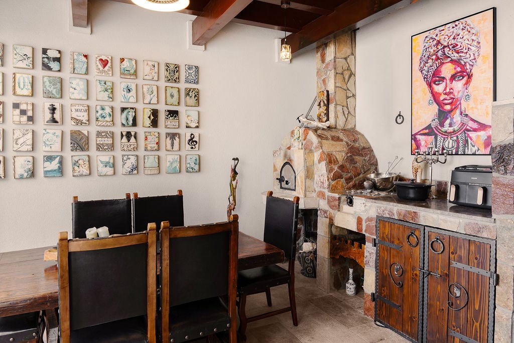 Living room in a Luštica townhouse, Montenegro: dining area with a wooden table, stone fireplace, and designer decor.