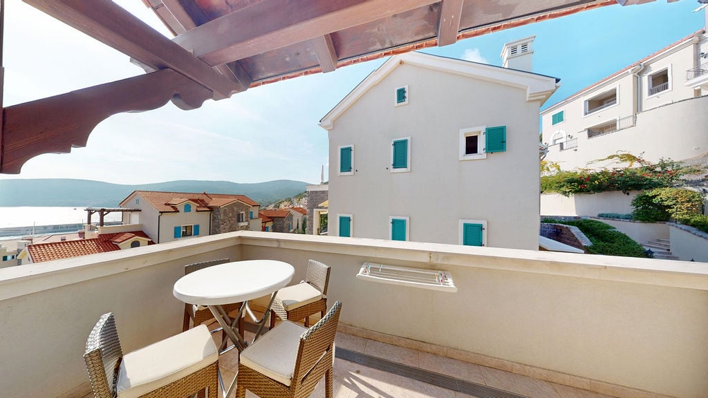 Cozy balcony with wicker furniture and a view of the sea and mountains in the Luštica residential complex, Montenegro.