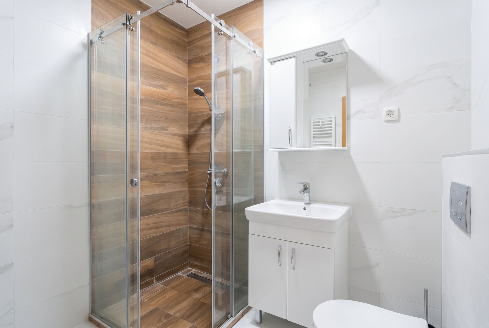 Modern bathroom featuring a glass shower enclosure, white vanity sink, and toilet.
