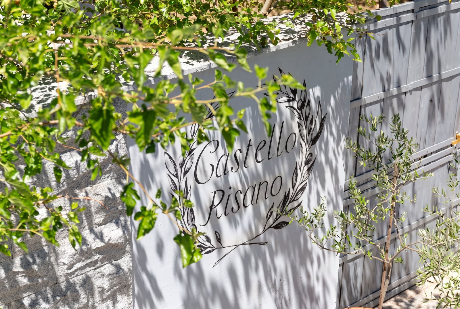 Signboard "Castello Risano" on a stone wall at the entrance to a residential complex in the town of Risan, Montenegro.
