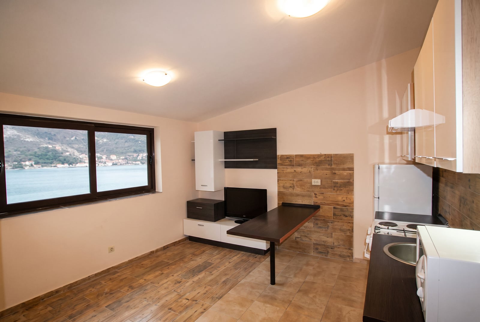 Kitchen-living room with furniture, TV, and panoramic sea view in a house in Tivat, Montenegro