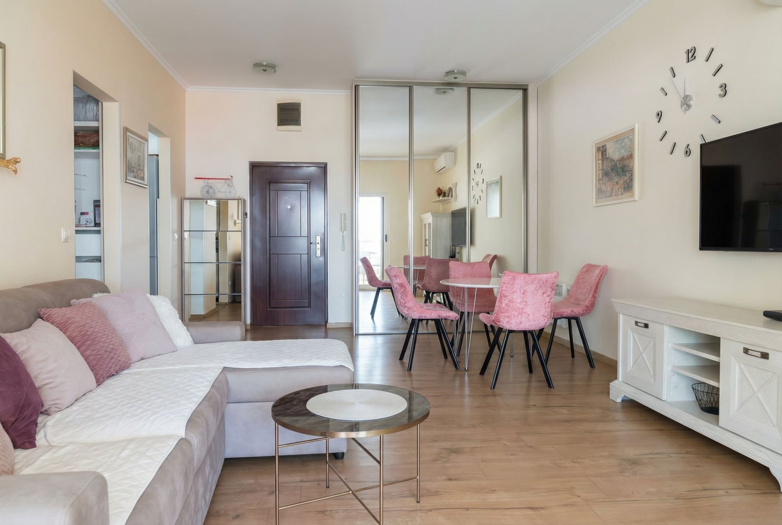 Living room in an apartment in Pržno, Montenegro: bright interior, corner sofa, dining area with pink chairs, and mirrors.