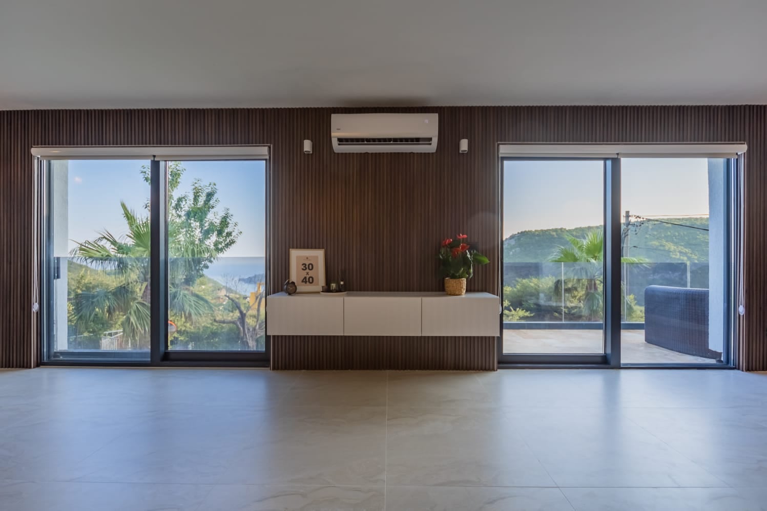 Living room with panoramic windows and sea view in a villa, Budva, Montenegro: modern interior with slatted panel.
