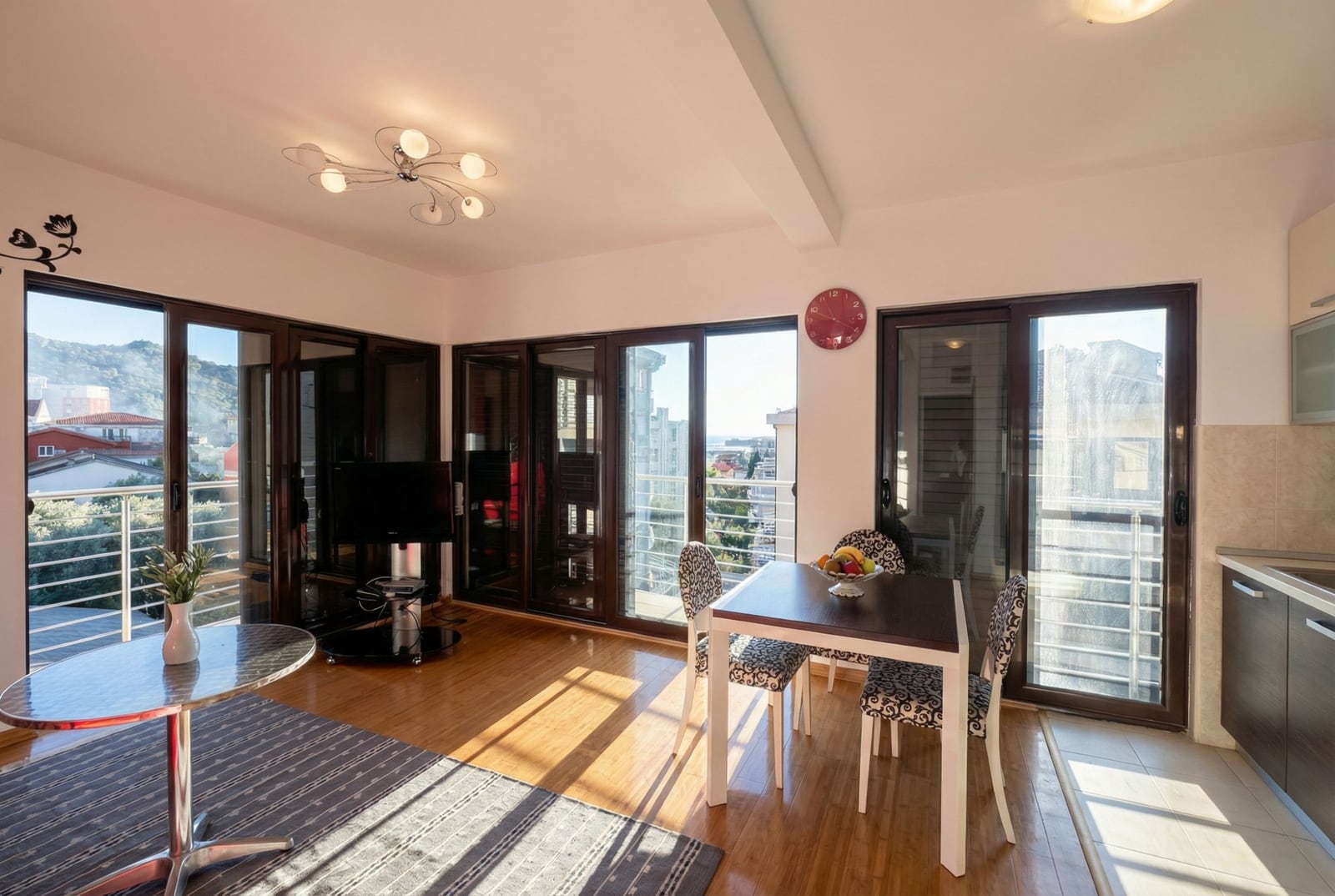 Bright living room with panoramic windows and access to the balcony in an apartment in Bečići, Montenegro: dining area and kitchen.
