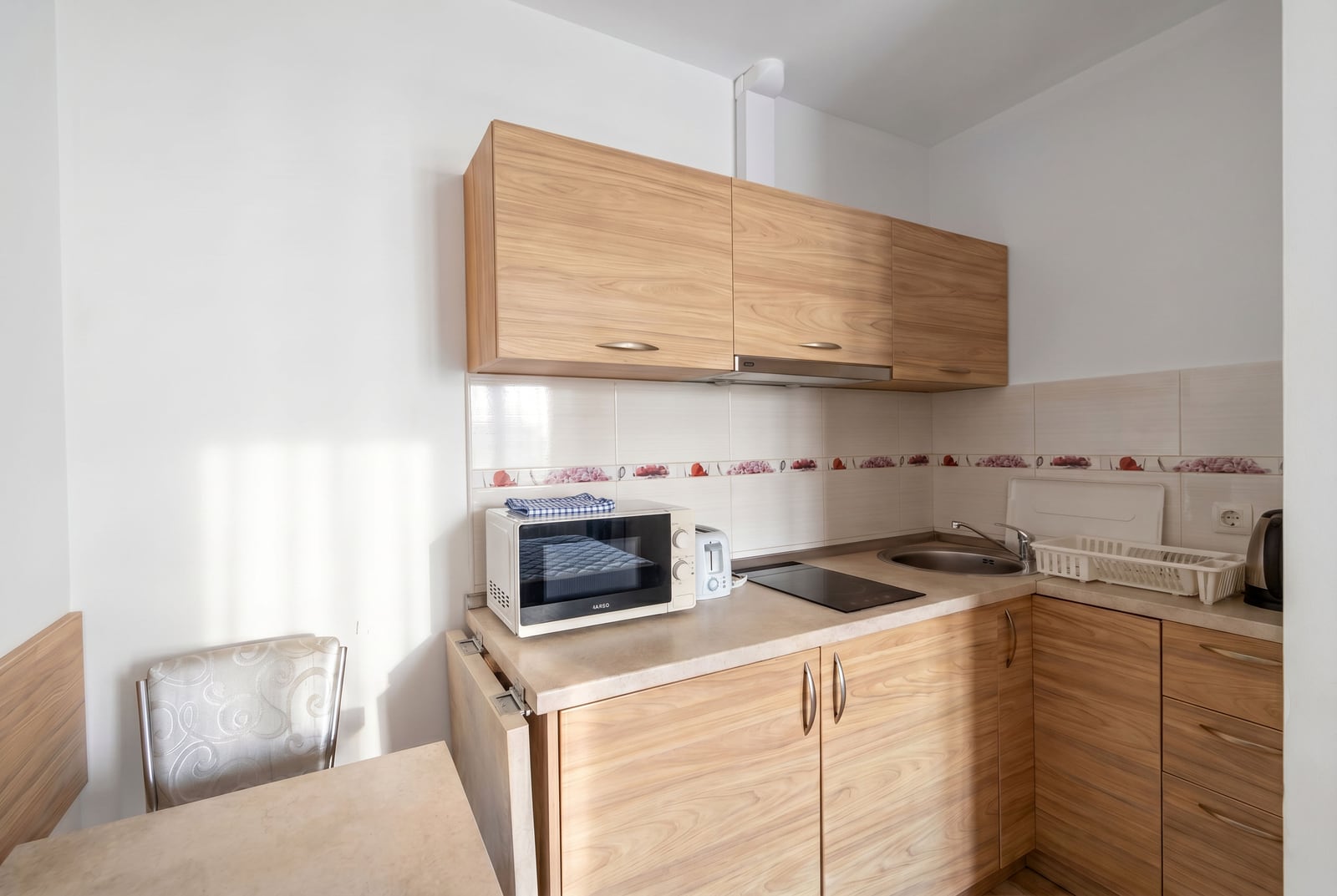 Compact kitchen with wooden cabinetry and appliances in an apartment for sale, Becici, Montenegro.