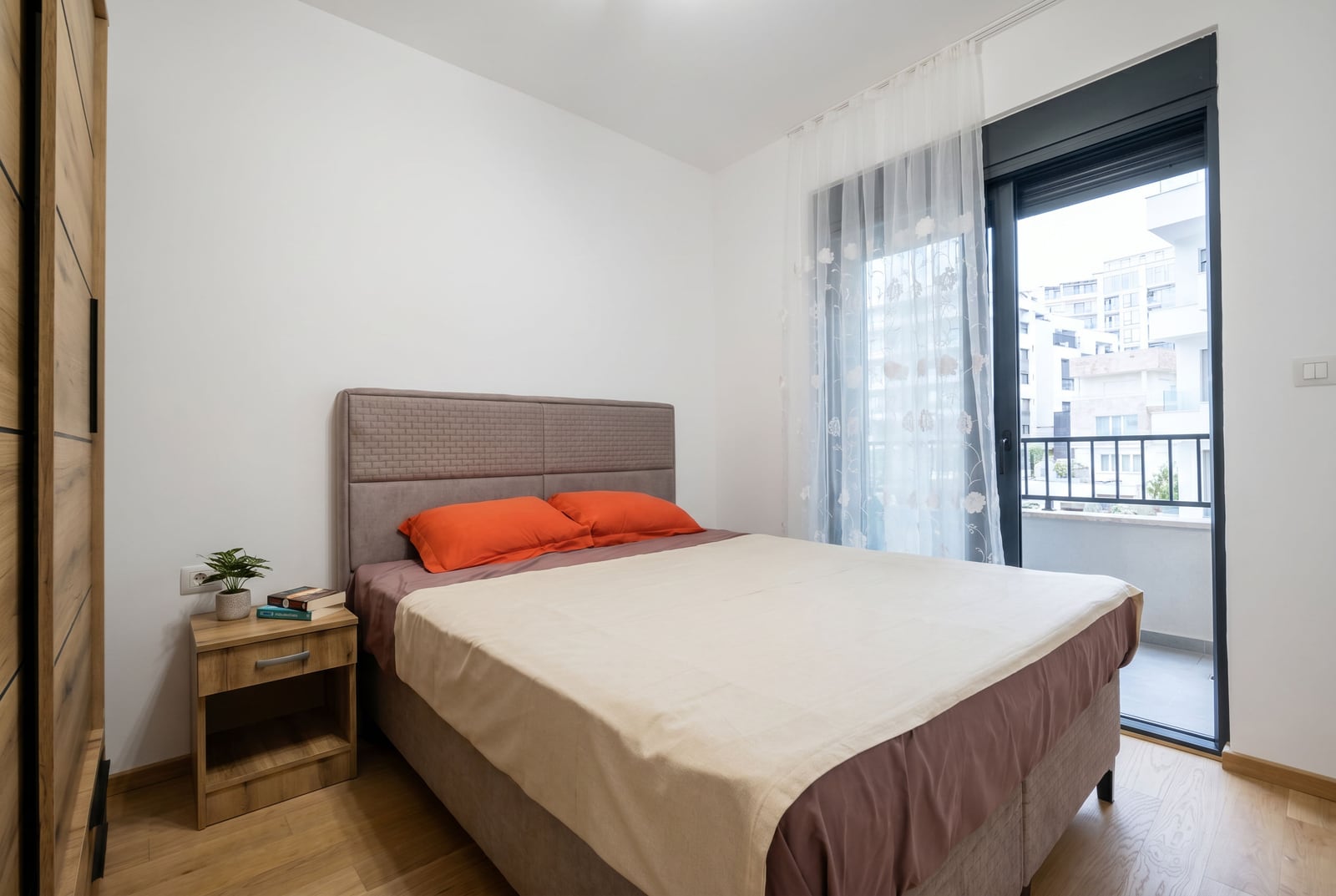 Modern bedroom with a double bed and balcony access in an apartment in Becici, Montenegro.