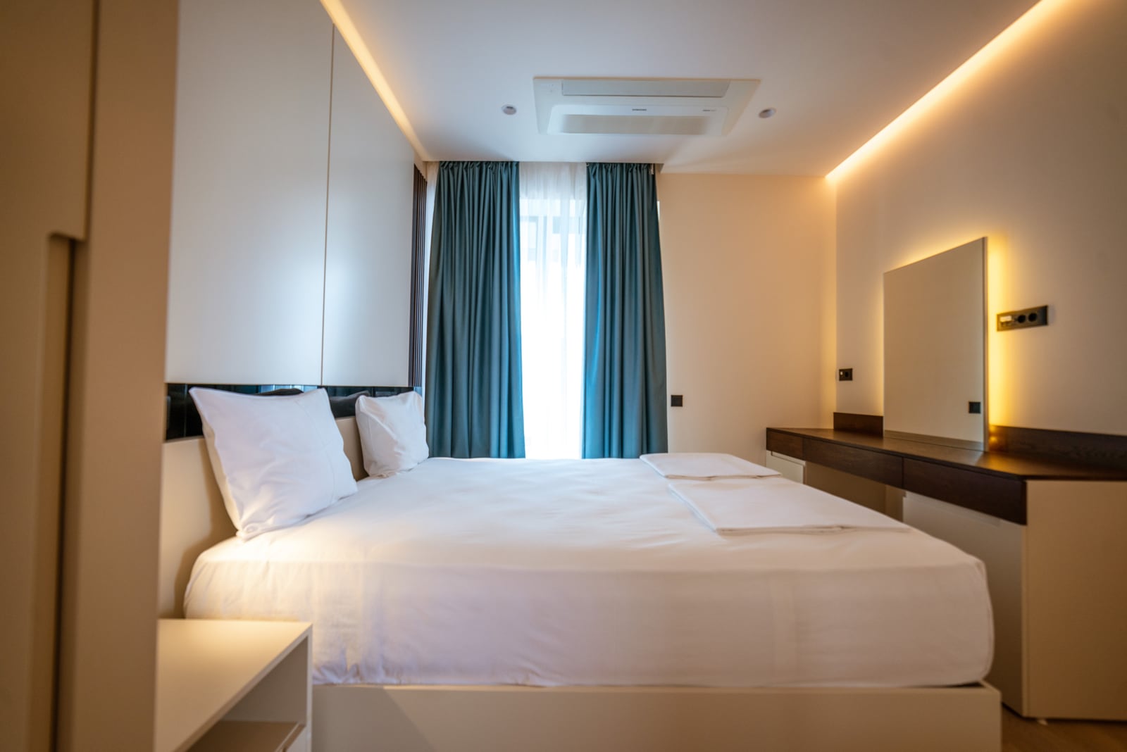 Modern bedroom in an apartment in Bečići, Montenegro: double bed, vanity table, and stylish lighting.