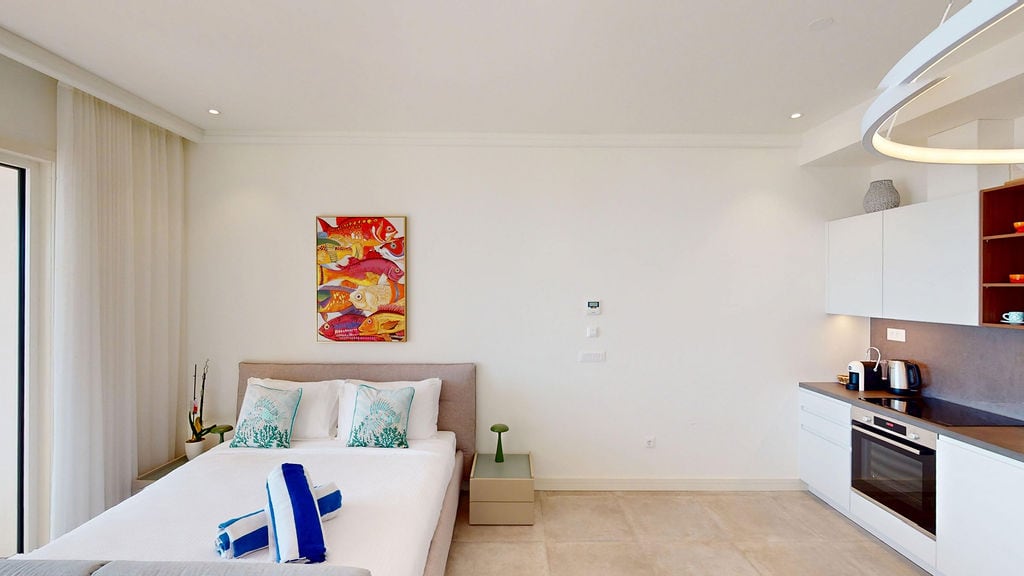 Modern bedroom with kitchen in Luštica apartments, Montenegro: double bed, light interior, and appliances.