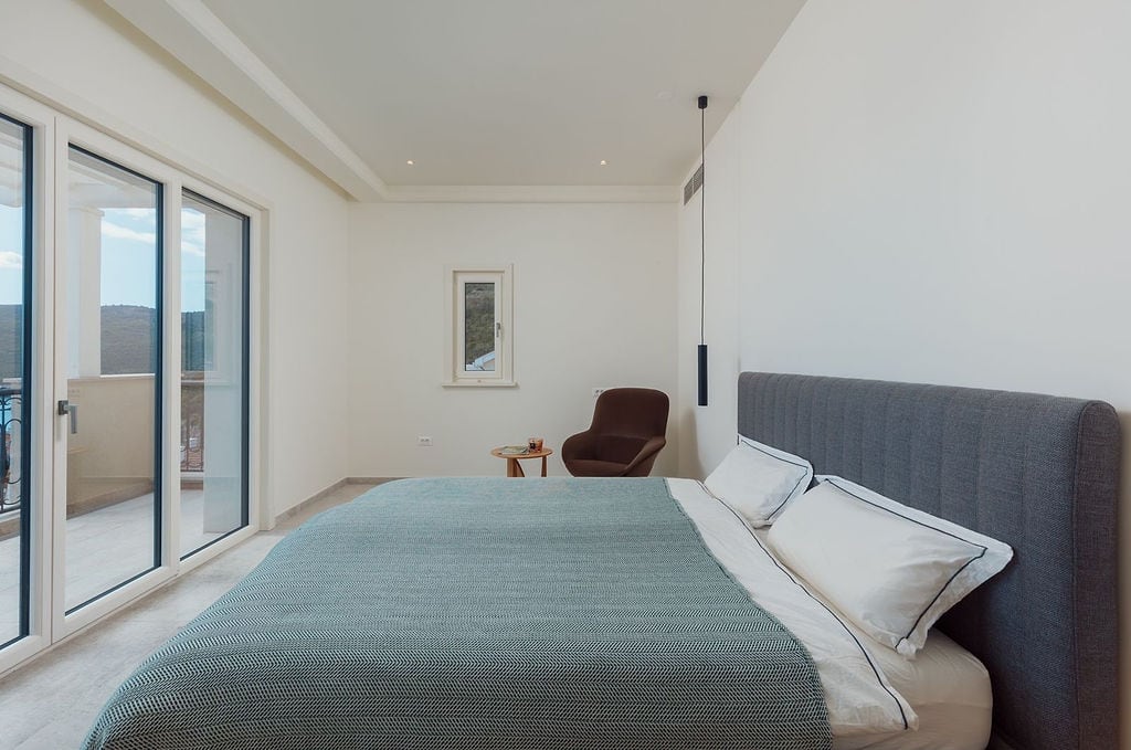 Modern bedroom with panoramic windows and terrace view at a villa in Luštica, Montenegro. Bright interior.
